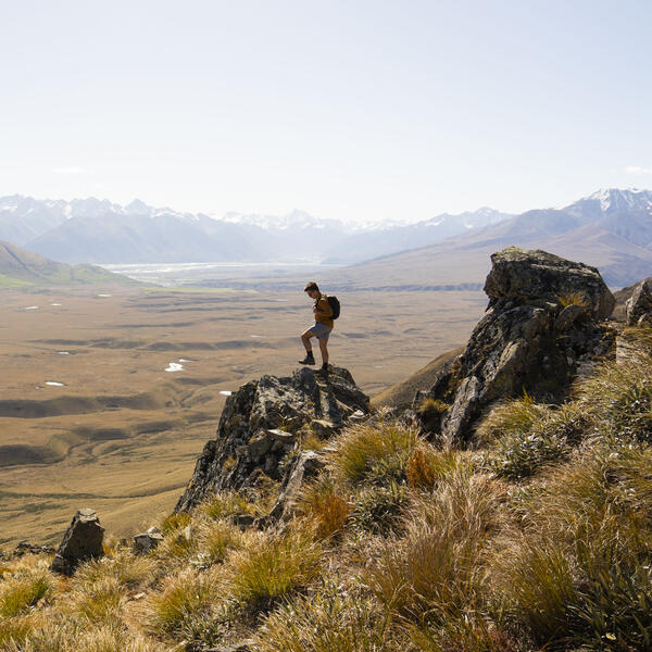 Aerial view of hiker on top of Mount Guy with views over Hakatere Conservation Park