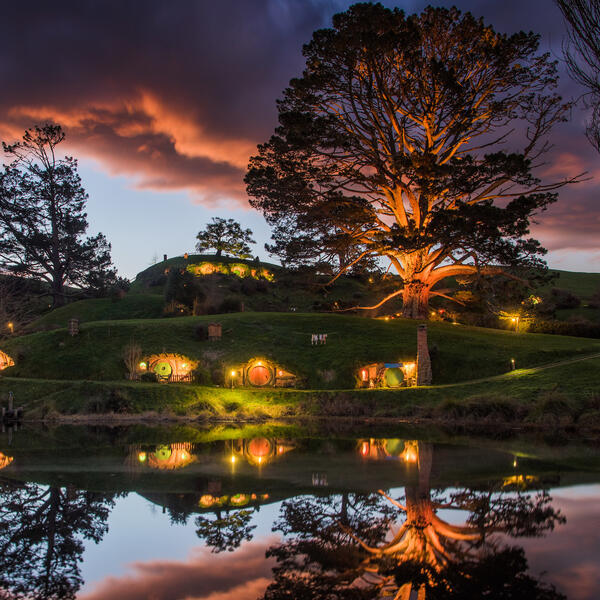 The Hobbiton™ Movie Set in the lush countryside setting of Matamata is a spectacular sight at sunrise or sunset.