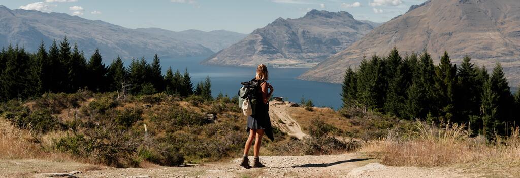 Woman admiring views on Lake Wakatipu and surrounding mountains from the top of the Queenstown Hill track