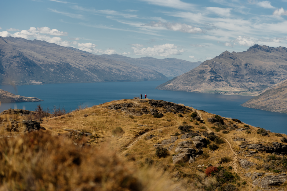 Hikers admiring views on Lake Wakatipu and surrounding mountains from the top of Quenstown Hill track