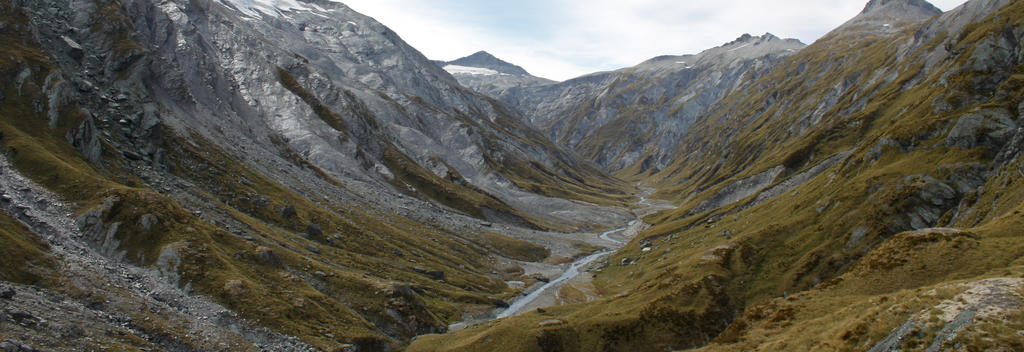 Lush river valleys are overshadowed by towering mountains.