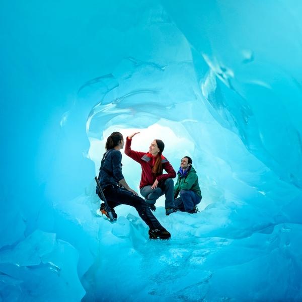 Step through ice tunnels lit by the sun at Franz Josef Glacier.