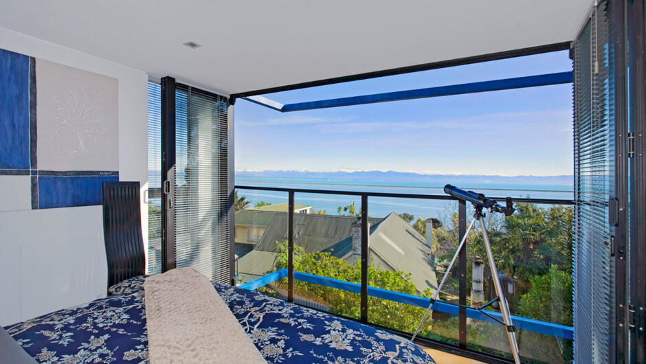 Master bedroom with Queen bed facing full-length glass bi-folds with fantastic sea views. Above a tinted skylight allows a view of the stars.