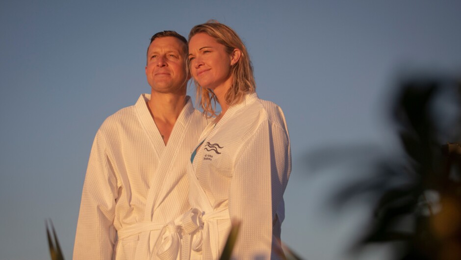 Couple looking out at the sunrise in robes.