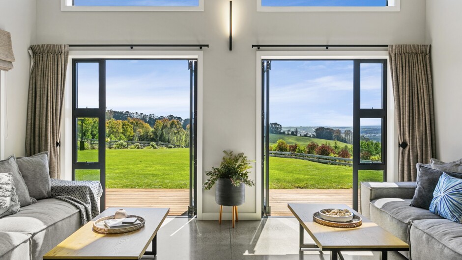 A seating area seamlessly extends from the kitchen under expansive gable ceilings, filling the space with abundant natural light.