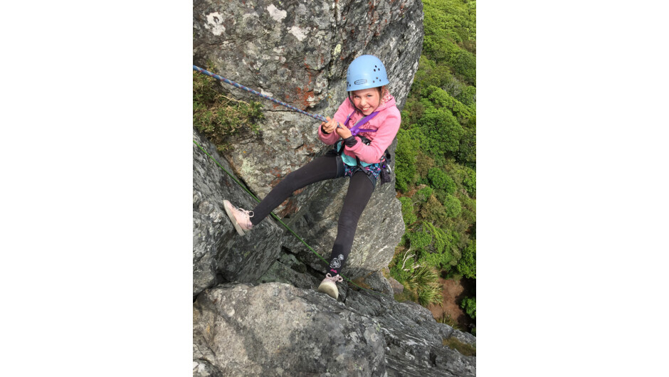 Linn, 8 year old girl abseiling on a rock face above Akaroa.