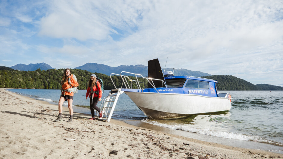 Walkers stepping off the Kepler Water Taxi onto Brod Bay, Kepler Track for a day walk.