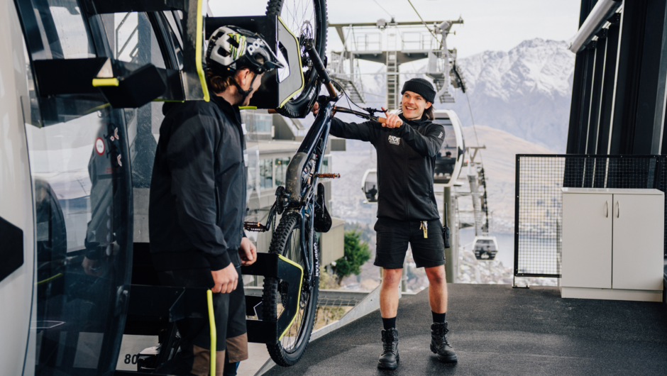 A staff member pulls a bike off the cabin at the top of the Gondola.