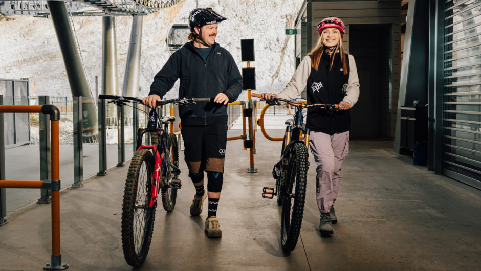 Two riders pushing their bikes on their way to the bottom of the Gondola.