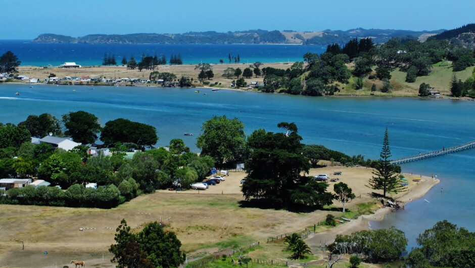 Whananaki Holiday Park situated on the left hand side in the centre of the photo with the famous footbridge on the right.